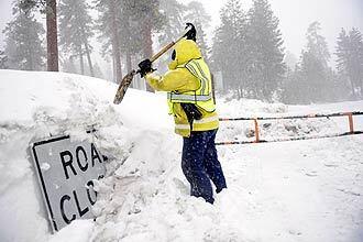 California Highway Patrol officer Jennifer Reneah digs out a sign on Highway 18 next to Snow Valley.