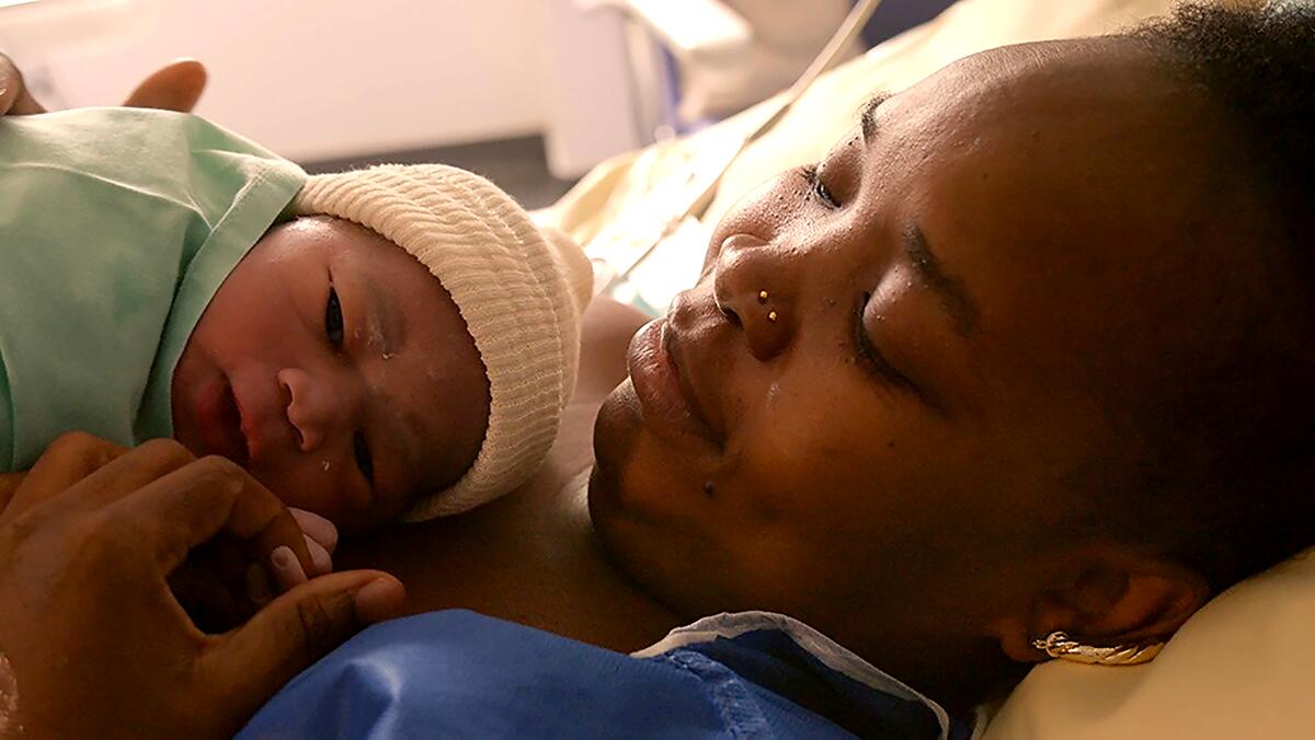 A woman holds her newborn baby close in a scene from the documentary "Our Body."