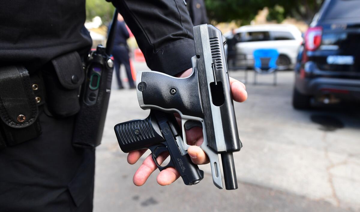 An officer displays recovered guns from residents turning in firearms 