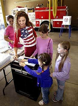 Cassandra Wyatt, 4, helps her mother place her ballot in the ballot box as her sisters watch. Ventura City Fire Station 1 is used as a polling site for elections. Station personnel moved one of the fire trucks to the outside parking lot to make room for voters.