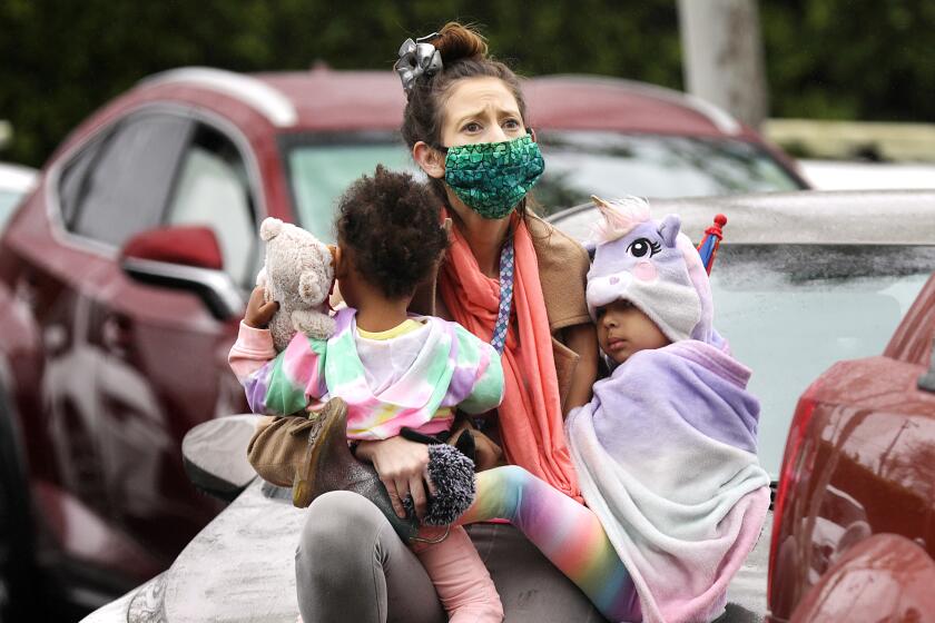 SANTA ANA-CA-APRIL 12, 2020: Ashley Amon, 33, and her daughters Alysha, 2, and Alexandria, 4, who are currently homeless, attend a gathering with fellow worshippers in their cars in a parking lot in Santa Ana to worship in an Easter service by Rev. Robert A. Schuller on Sunday, April 12, 2020. Schuller is reviving a practice that launched his father to worldwide acclaim- the drive-in ministry. For the past four years, the younger Schuller has been preaching primarily on social media, providing daily sermons from his "church with no walls." The COVID-19 outbreak - and the loss of in-person fellowship - led him back to his roots. "People need a place to go to worship on Easter, " he said. (Christina House / Los Angeles Times)