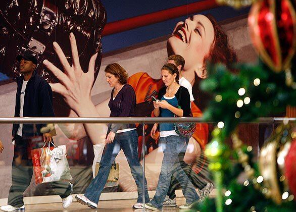 Shoppers pass a giant mural inside South Coast Plaza in Costa Mesa on Friday.