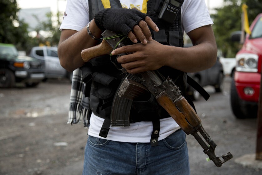 A member of a "self-defense" group in the Mexican state of Michoacan stands guard recently at a checkpoint at the entrance to the town of Antunez.