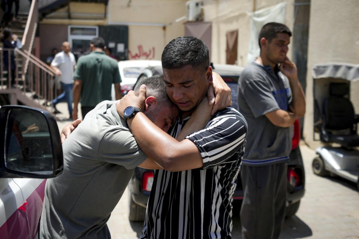 Two grieving men embrace.