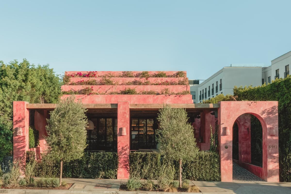 An exterior photo of a verdant salmon-pink building.