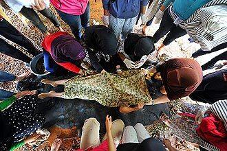 Volunteers carry the body of a dam collapse victim at a makeshift morgue. Dozens of people remain missing.