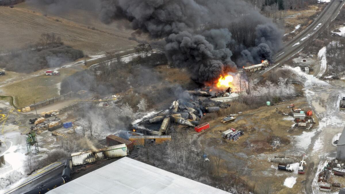 In and aerial shot, flames and smoke are seen at the site of a freight train derailment. 