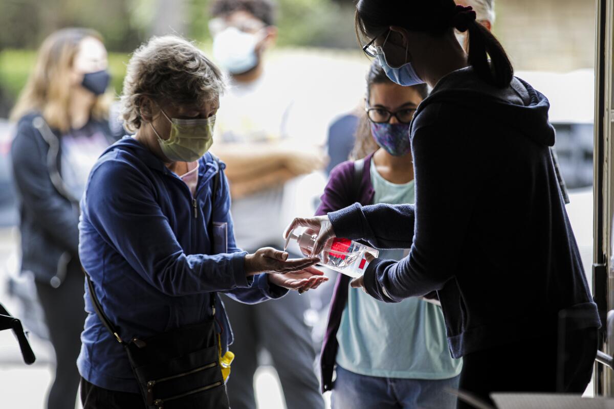 A woman in a face mask accepts hand sanitizer