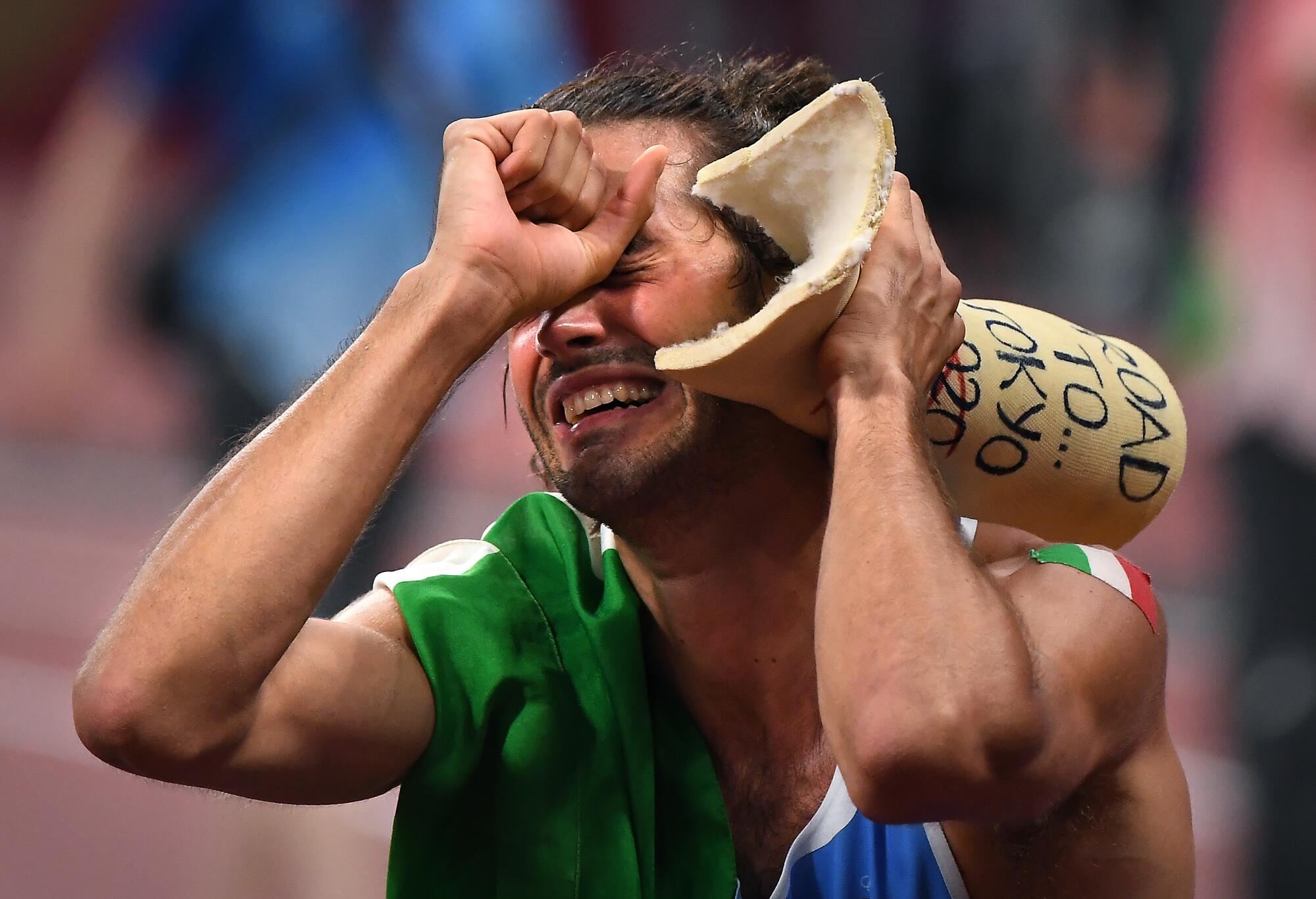 Italy's Gianmarco Tamberi celebrates his gold medal in the high jump by holding a cast from an ankle injury.