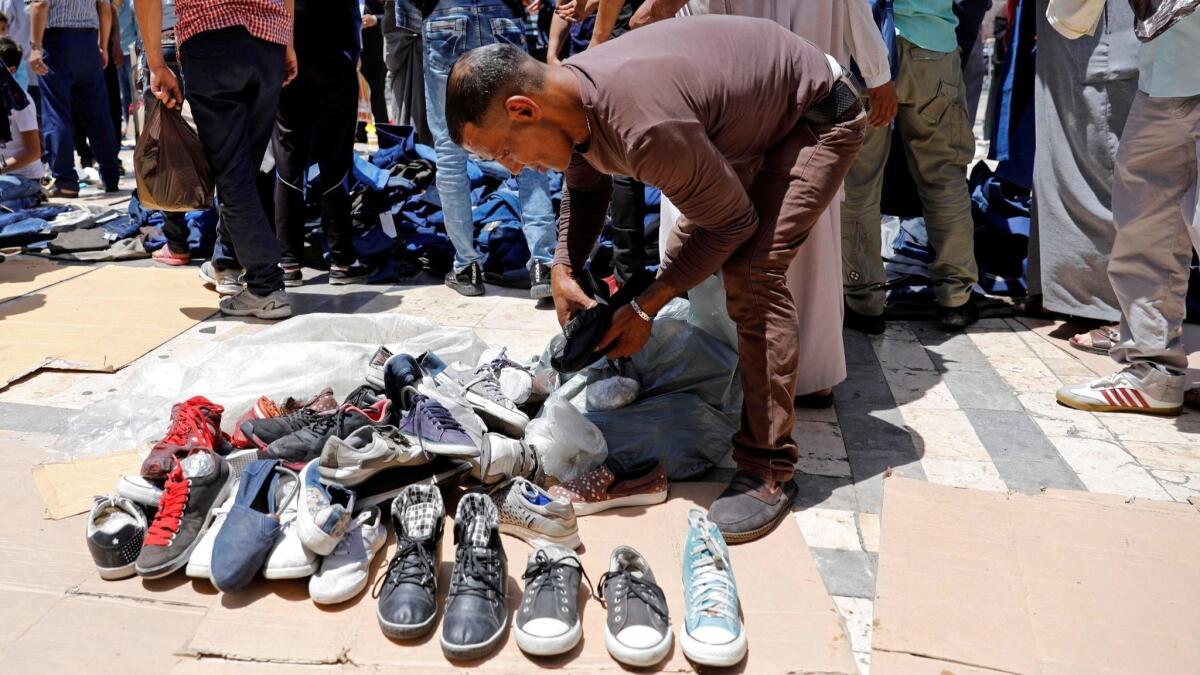 Jordanians buy secondhand shoes in an open-air market in central Amman on June 8, 2018.