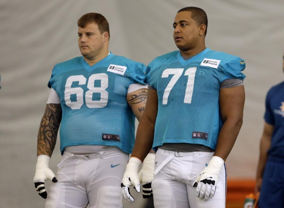 In this July 24, 2013 file photo, Miami Dolphins guard Richie Incognito (68) and tackle Jonathan Martin (71) stand on the field during practice.