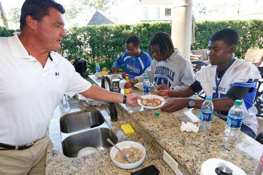 Former USC coach Ed Orgeron serves a bowl of gumbo to Mandeville High football player Darren Steele at his home this fall.