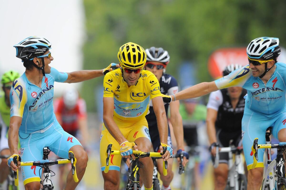 Vincenzo Nibali of Italy, wearing the leader's yellow jersey, is congratulated by his fellow riders as he crosses the finish line of the 21st stage of the Tour de France.