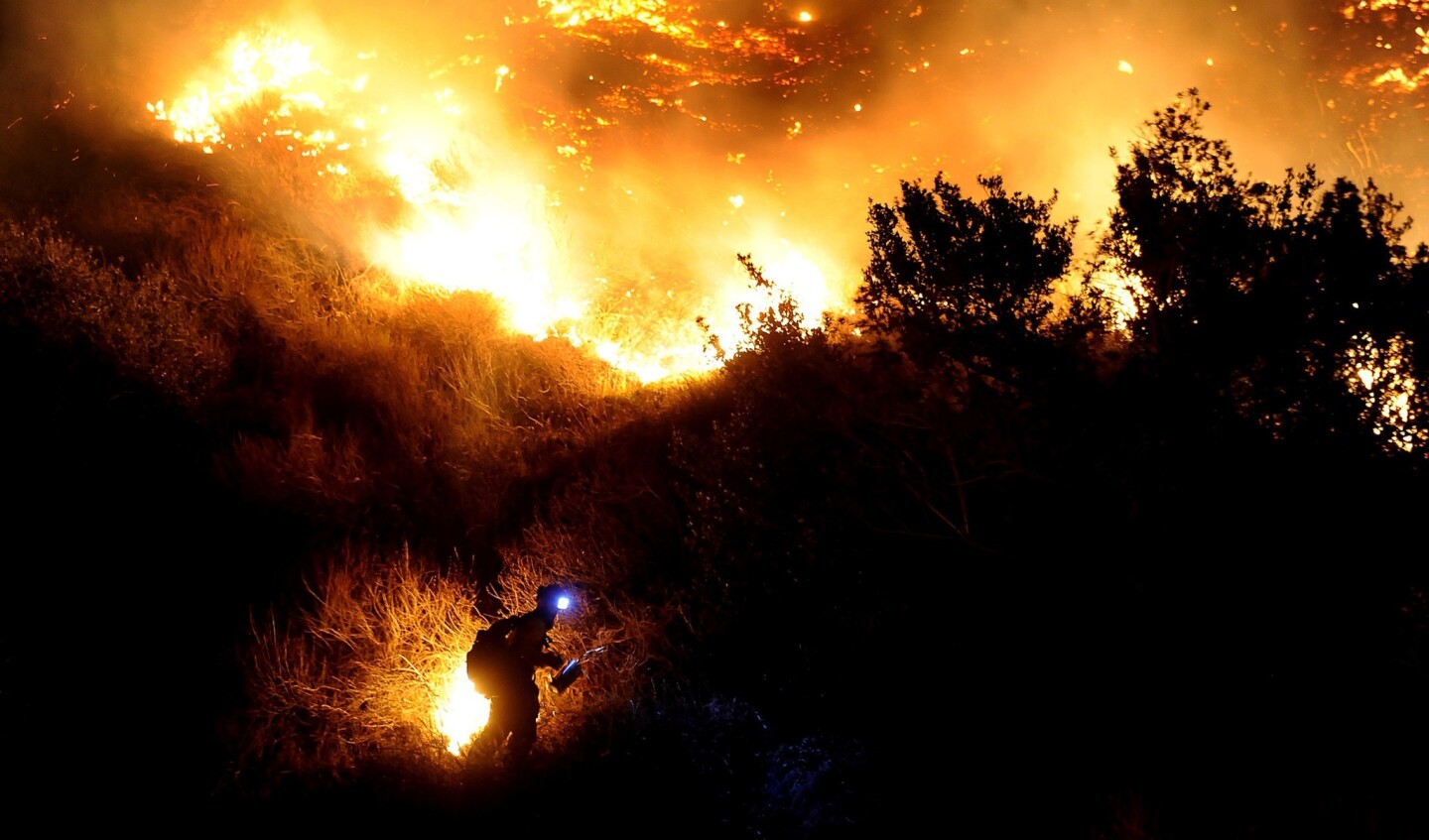 A firefighter starts a backfire along San Gabriel Canyon Road in Azusa as the Colby fire burns through brush in January.