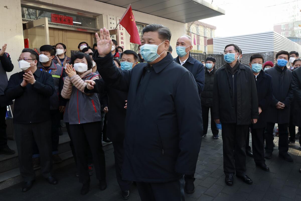 El presidente chino, Xi Jinping, con una máscara facial protectora, saluda mientras inspecciona el nuevo trabajo de prevención y control de la neumonía por coronavirus el 10 de febrero en un vecindario de Beijing. (Pang Xinglei / Associated Press).