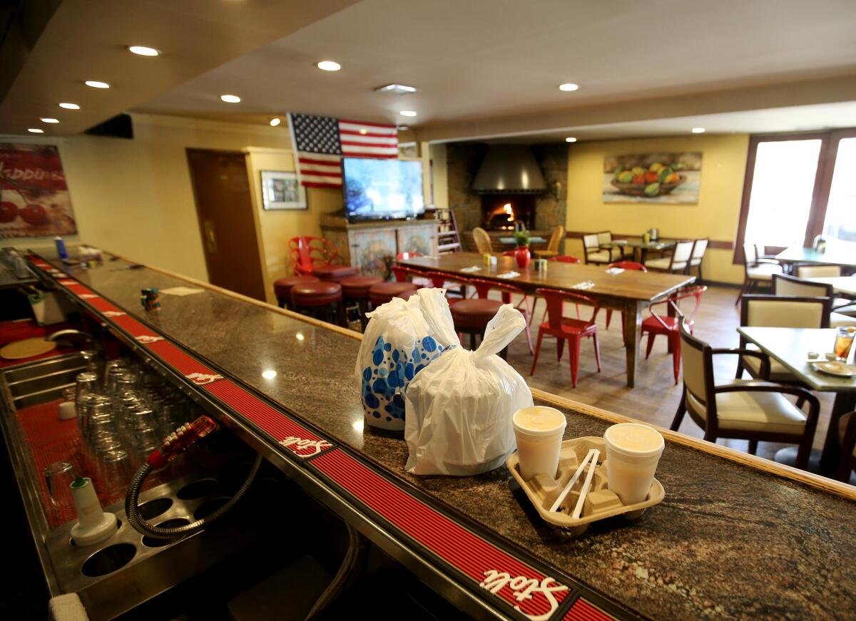 Because of novel coronavirus precautions restricting restaurants from serving dine-in customers, a to-go order waits for pickup at an empty Dish restaurant, in La Cañada Flintridge on Tuesday.