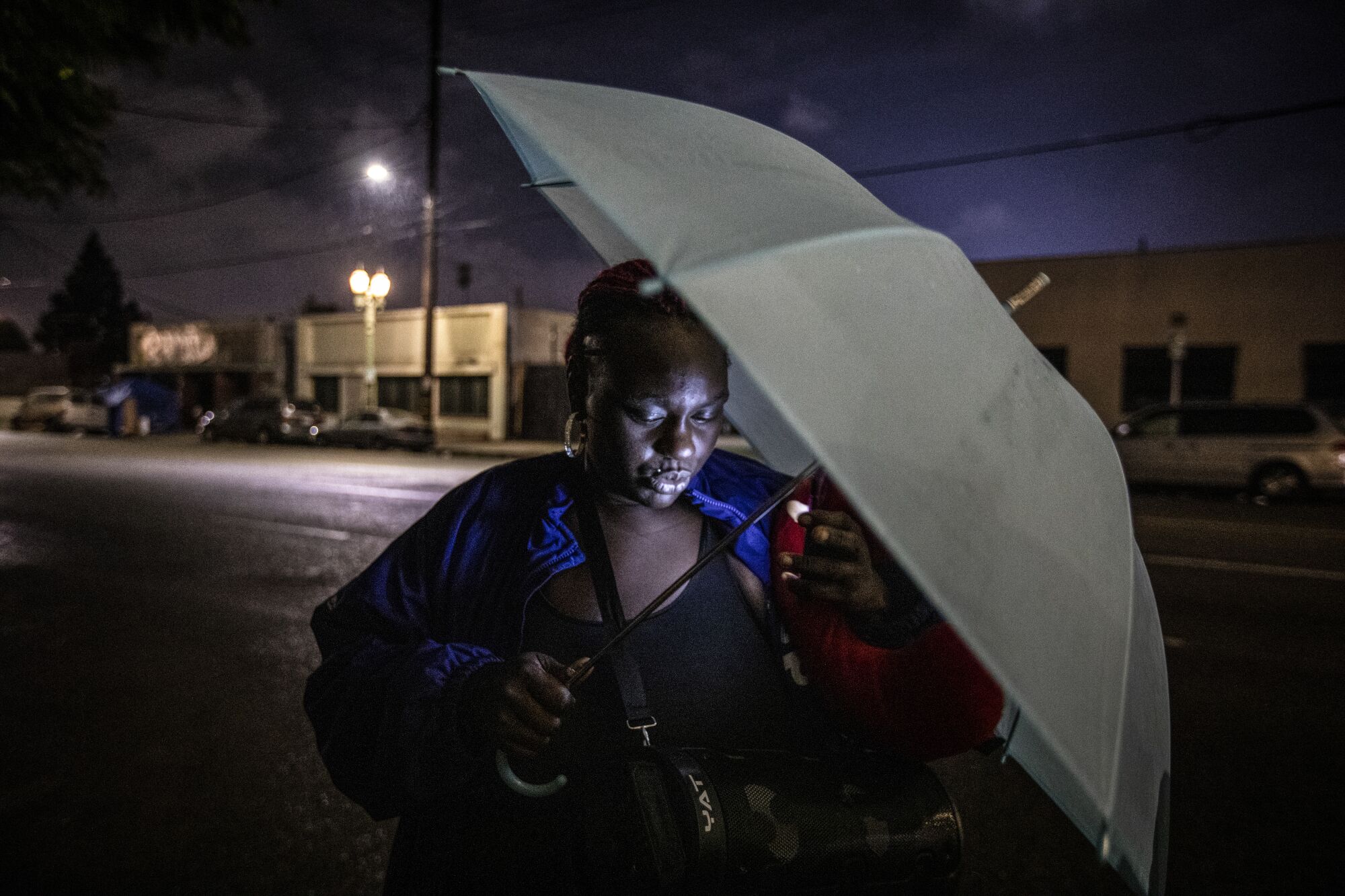A woman holds an umbrella as a cell phone illuminates her face