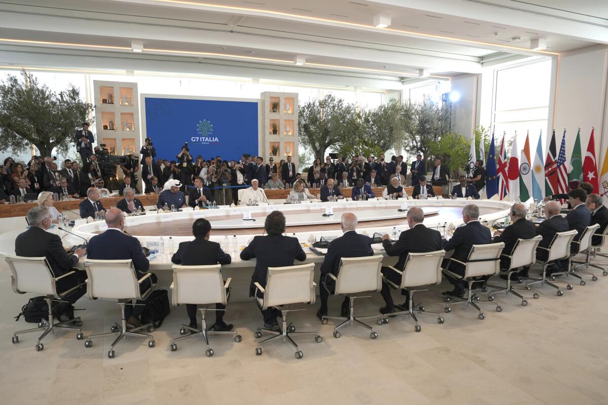 G-7 world leaders and others from guest nations sit around a massive circular table. 