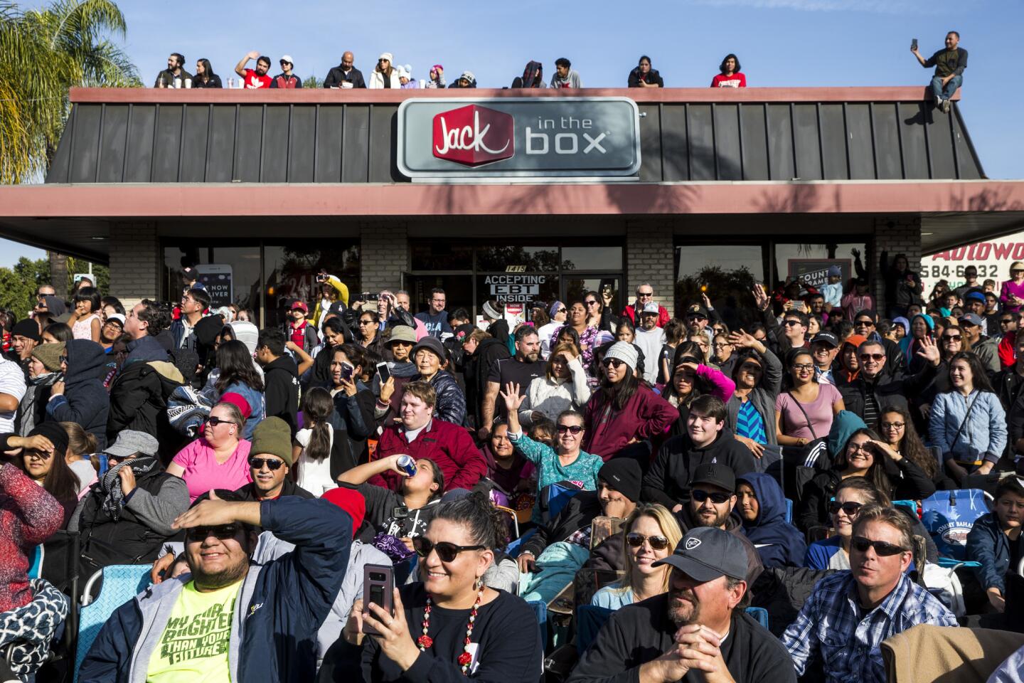 People pack the sidewalk and roof along the Rose Parade route on Colorado Blvd. in Pasadena.