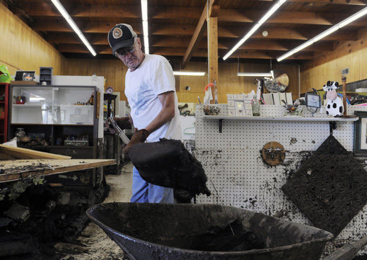 Bob Paetzel scoops mud out of a collectibles store in Loveland, Colo., where floodwaters are receding and rescue and recovery efforts ongoing.