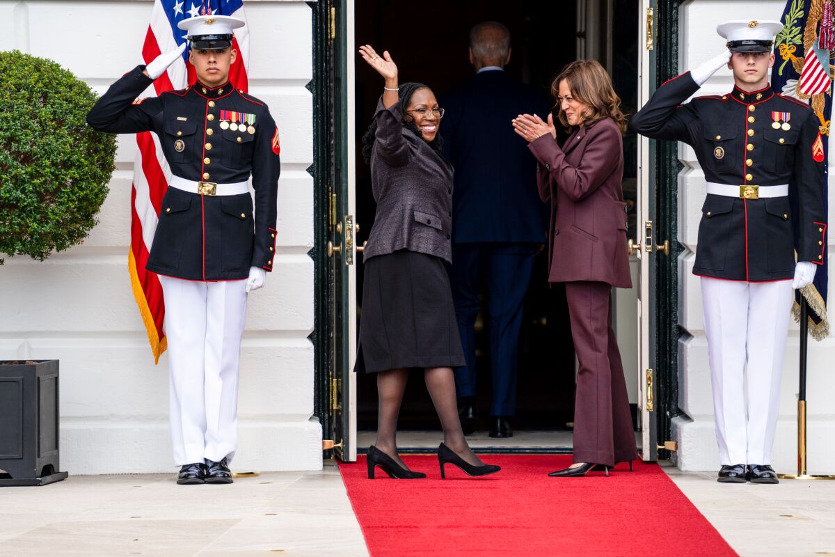 Ketanji Brown Jackson turns and waves as she enters the White House with Vice President Harris, as Marines stand by saluting.