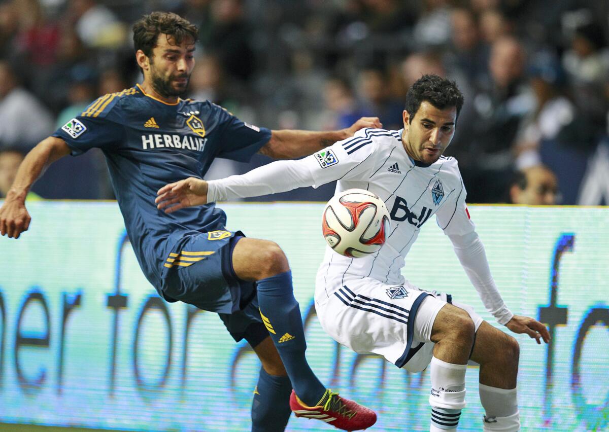 Galaxy's Baggio Husidic and Vancouver Whitecaps' Steven Beitashour try to get possession of a loose ball on April 19.
