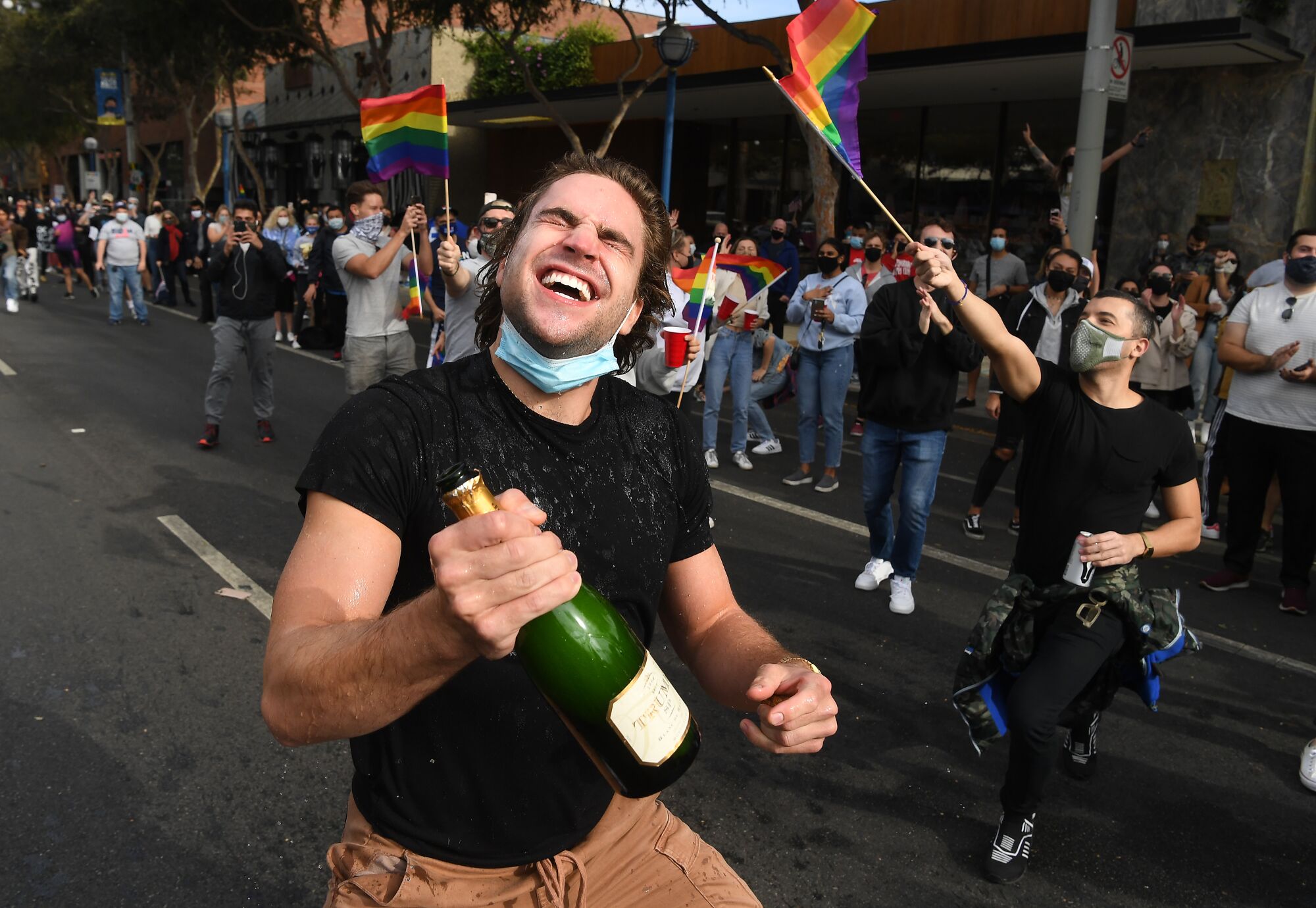 A man in West Hollywood pops open a bottle of Champagne to celebrate Joe Biden's win.