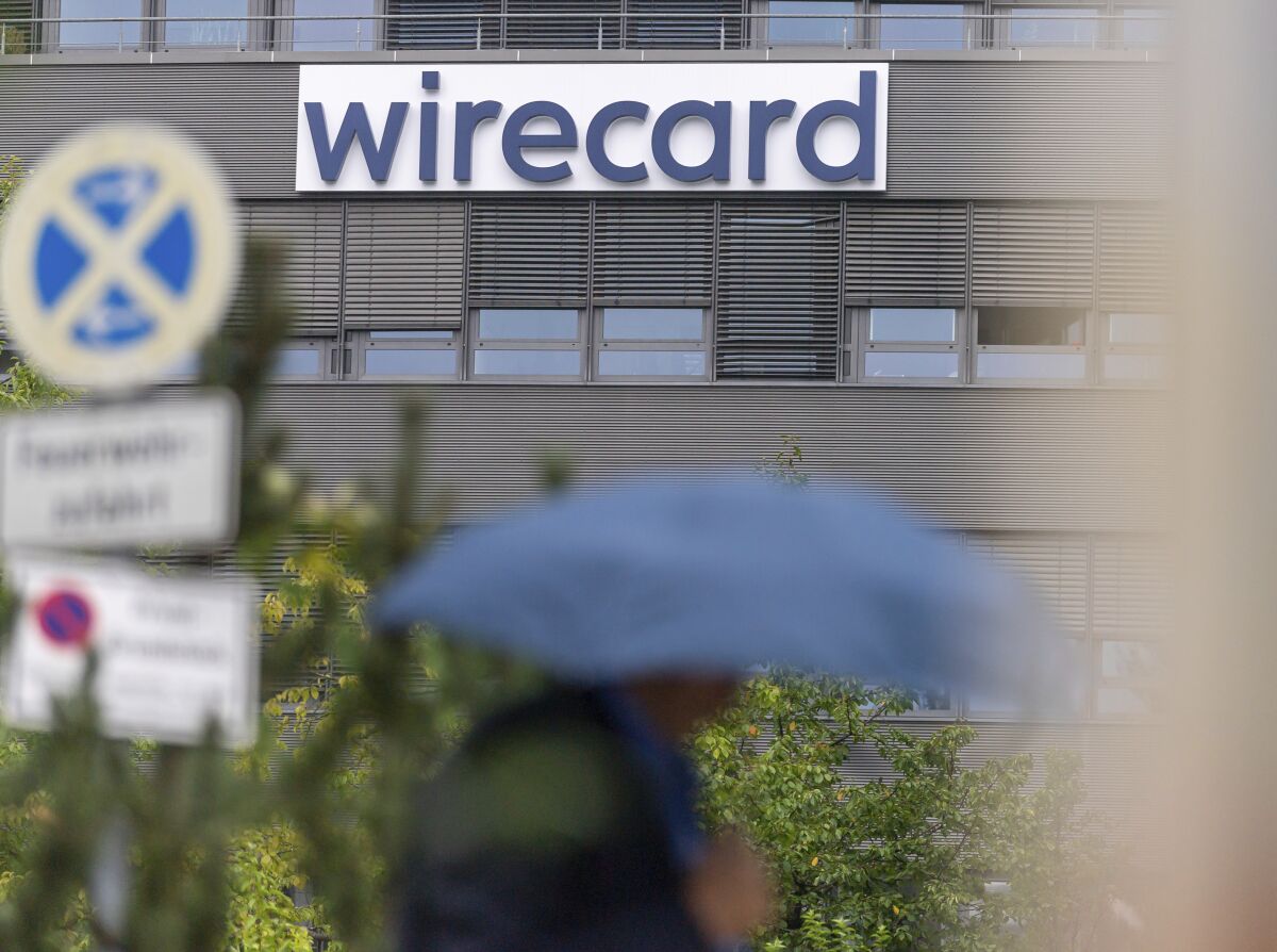 A person walk in front of a building with the logo of the insolvent company Wirecard in Aschheim near Munich, Germany, Tuesday, Sept. 1, 2020. German opposition parties plan to force the launch of a parliamentary inquiry into the downfall of bankrupt payment company Wirecard. (Peter Kneffel/dpa via AP)