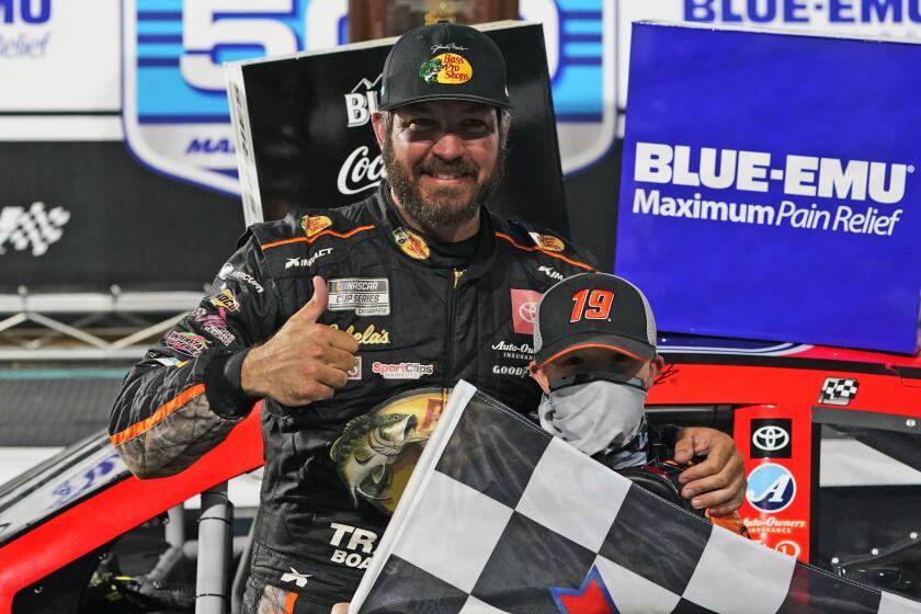 Martin Truex Jr. (19) celebrates with a fan after winning the NASCAR Cup Series.