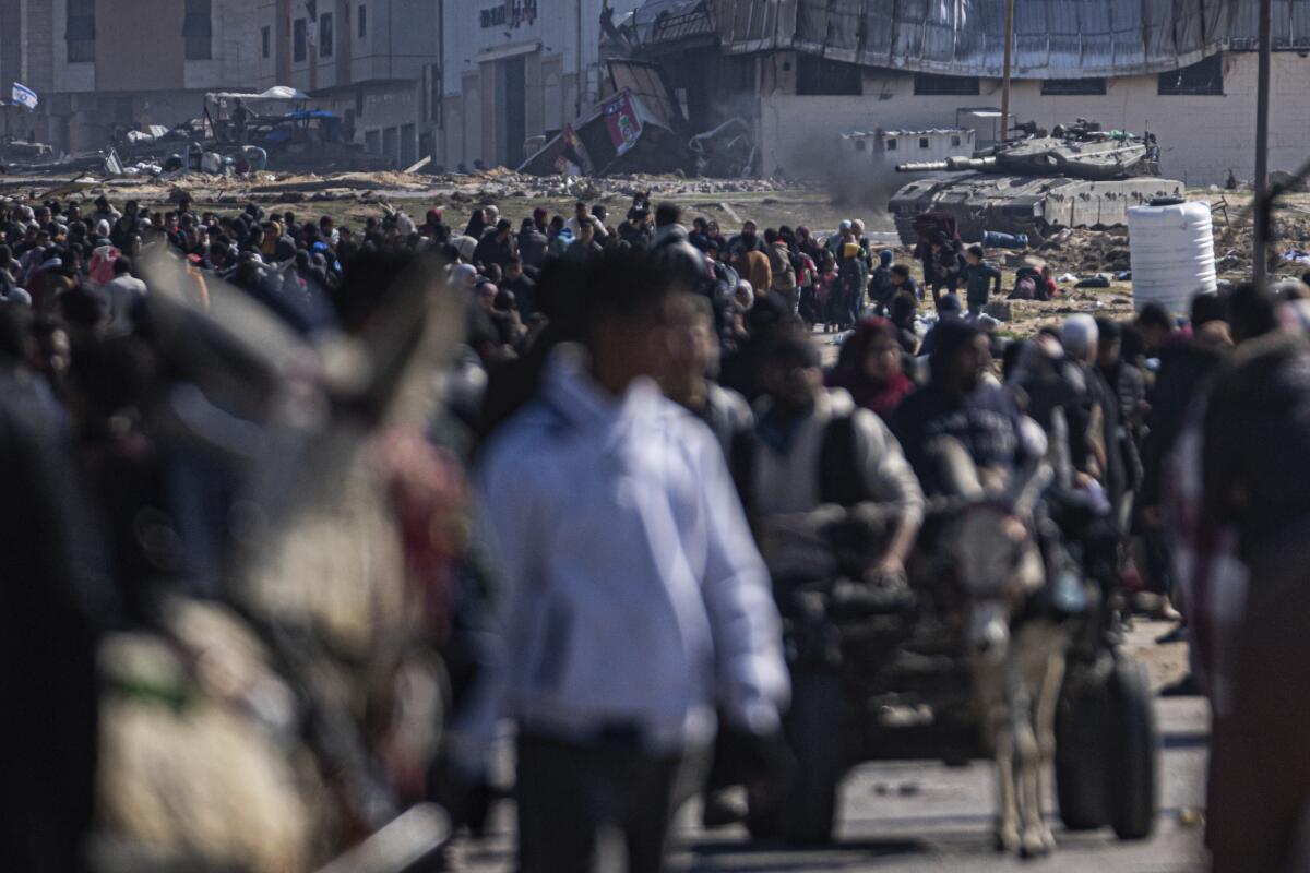 Un tanque del ejército israelí toma posición mientras un grupo de palestinos llegan a la ciudad de Rafah, 