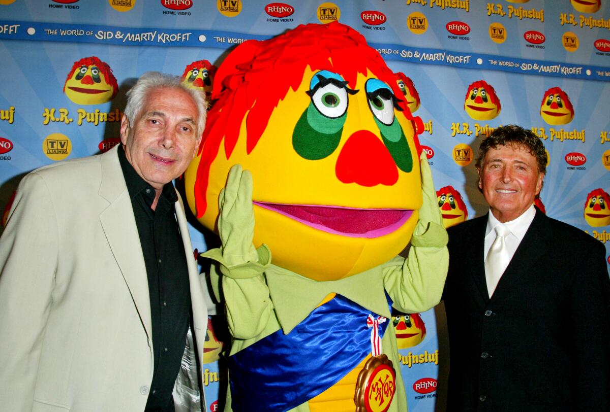 Marty Krofft with H.R. Pufnstuf, a yellow life-size puppet with orange hair, and Sid Krofft.