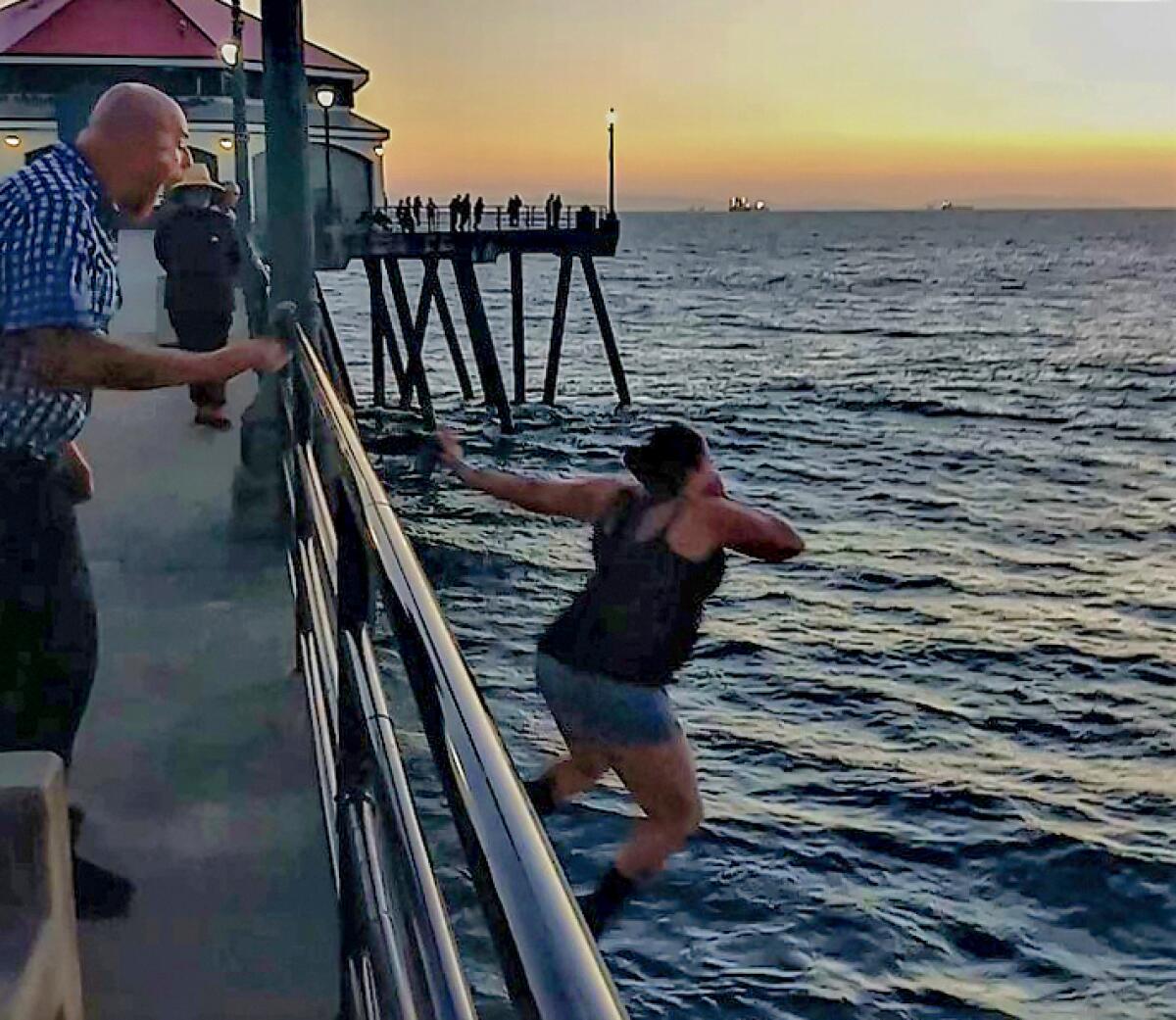 Fenton Dee III shouts at a woman in his company as she jumps off the Huntington Beach Pier Sunday. 