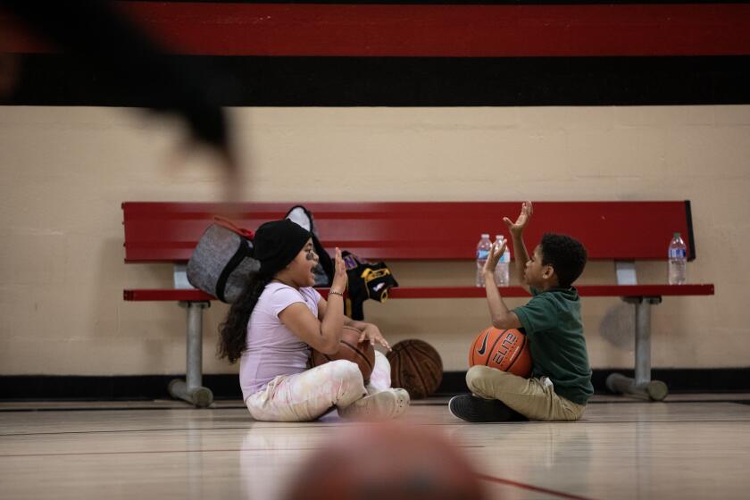 San Diego, California - February 19:Pandora Maulupe, left, and Messiah Sutton spend time together as their siblings participate in basketball practice at Encanto Recreation Center on Monday, Feb. 19, 2024 in San Diego, California. The Suttons were part of a guaranteed income program which ended earlier in the month. The program provided that family with $500 a month for two years. (Ana Ramirez / The San Diego Union-Tribune)