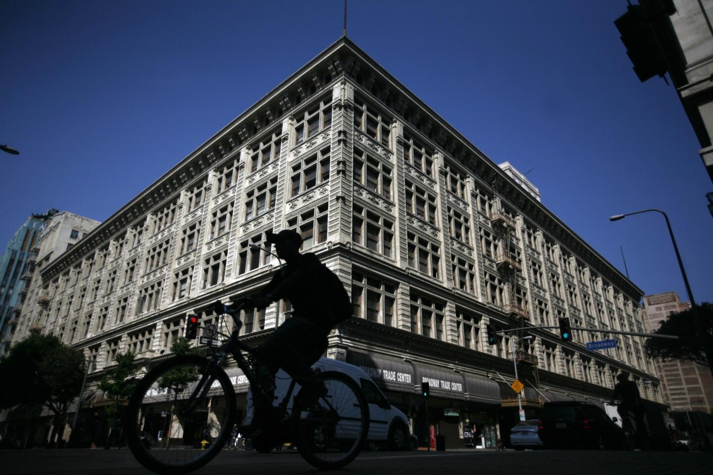A bicyclist passes the corner of 8th and Broadway, where the Broadway Trade Center, an enormous 100-year-old building that was once the May Co. department store, may soon be up for sale. The now run-down building may be converted to housing, hotel, office and retail use.