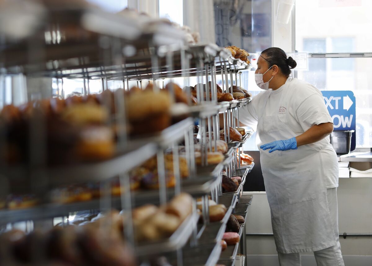 Longtime employee Lourdes Moreno fills trays at Peterson's Donut Corner in Escondido.