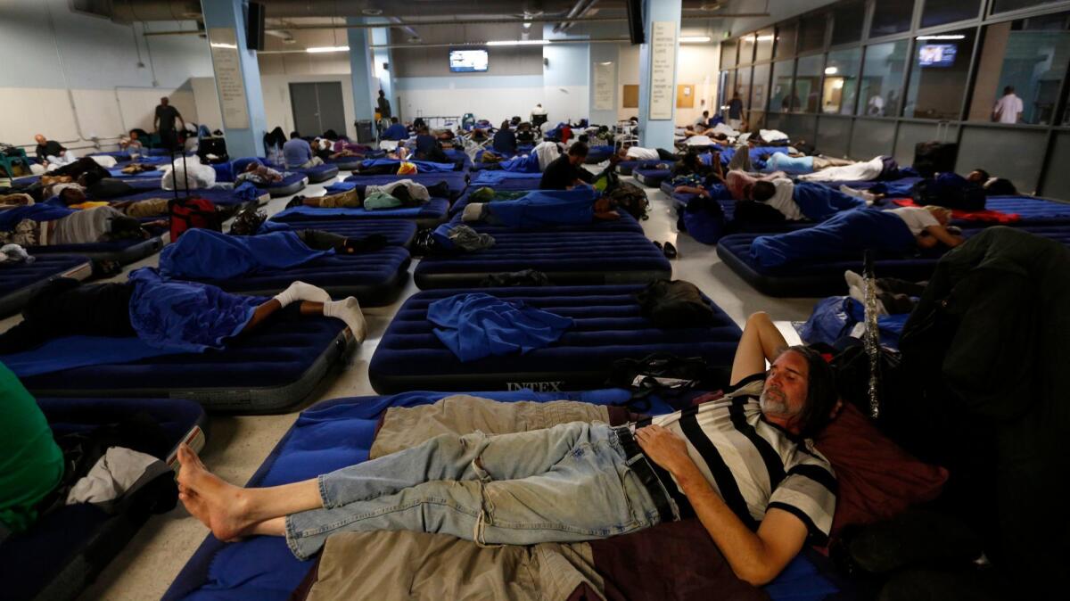 Kurt Kruhlinski, 53, foreground, joins dozens of other homeless men in the day room that is now being used in the evening for emergency bedding at the Union Rescue Mission.