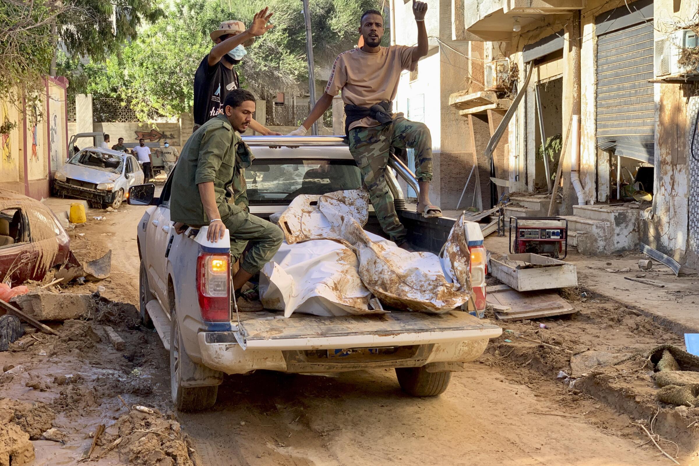 Three men in the back of a pickup with bodies in bags