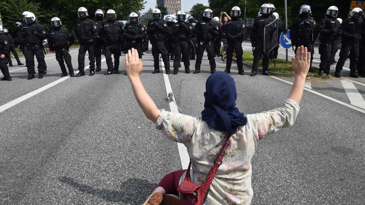 A demonstrator faces police officers during a July 7 protest in Hamburg Germany.