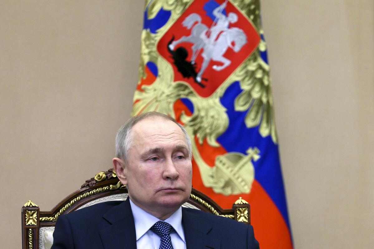 Russian President Vladimir Putin sits in a gilt chair.