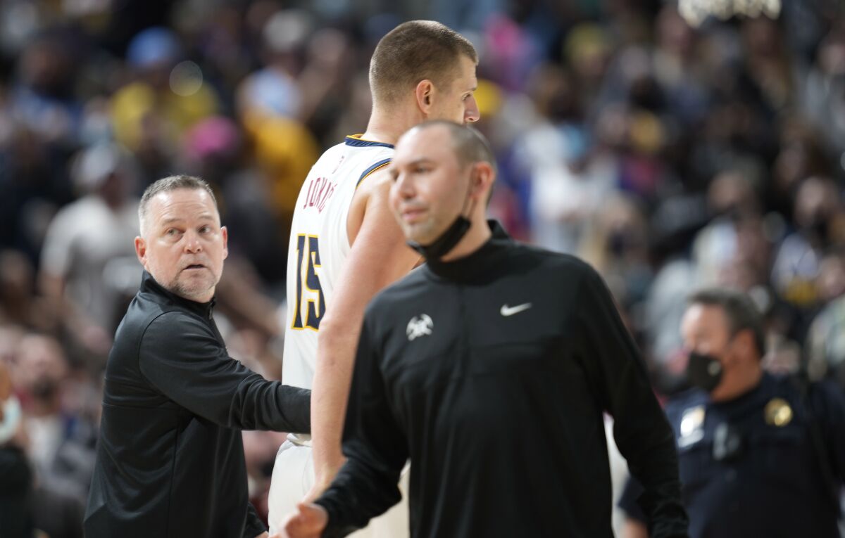 Denver Nuggets head coach Michael Malone, left, guides center Nikola Jokic to the bench after Jokic was involved in an altercation with Miami Heat forward Markieff Morris in the second half of an NBA basketball game Monday, Nov. 8, 2021, in Denver. Jokic was ejected for his part in the incident. (AP Photo/David Zalubowski)
