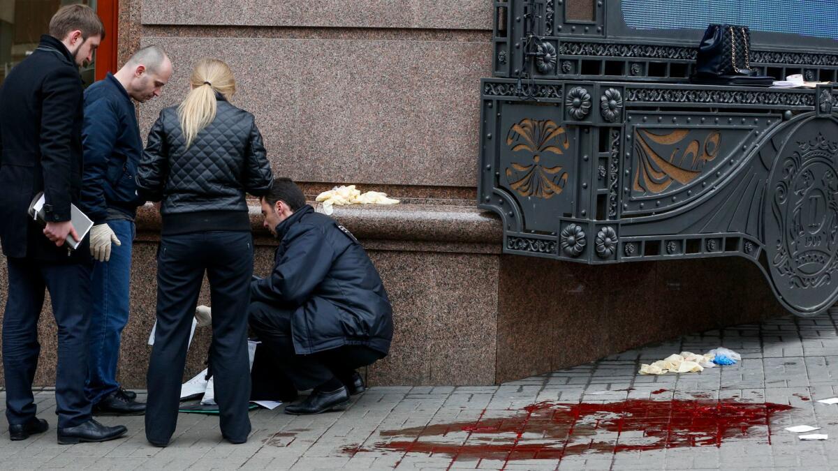 Forensics experts and police officers examine the scene where Denis Voronenkov was killed in Kiev, Ukraine, on March 23.