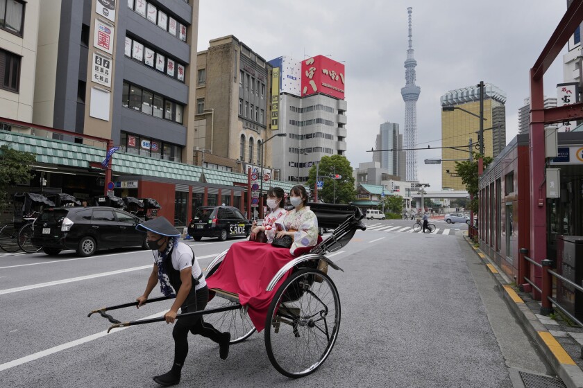 A rickshaw puller carries his customers around Tokyo's Asakusa area famous for sightseeing, Wednesday, June 22, 2022. Japan is bracing for a return of tourists from abroad, as border controls to curb the spread of coronavirus infections are gradually loosened. (AP Photo/Hiro Komae)