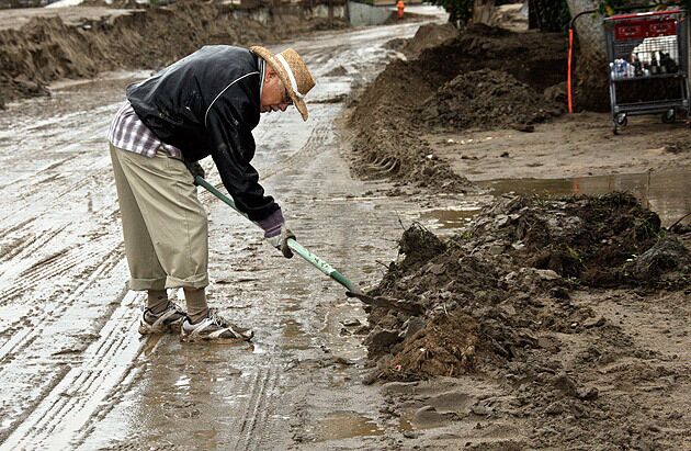 On Tyler Street in Highland, homeowner Magdaleno Aguirre, 75, shovels mud. See full story