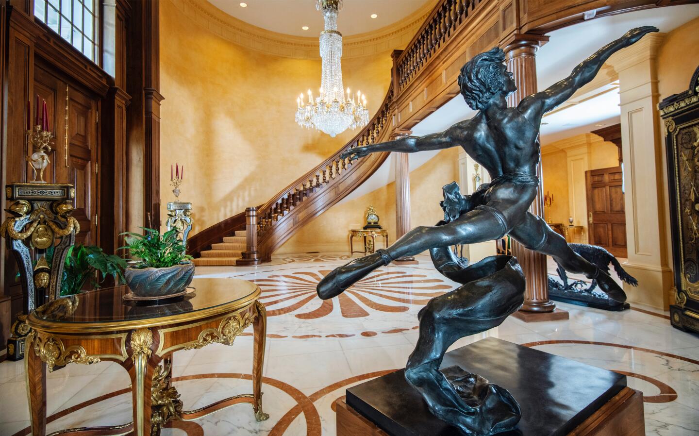 A sculpture of a leaping figure is seen in front of a grand staircase in the foyer.