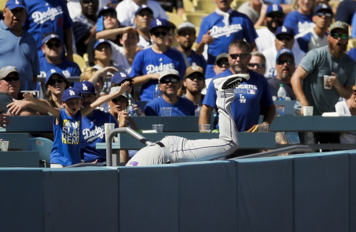 Colorado's David Dahl dives into the stands to catch a fly ball hit by Dodgers' Yasmani Grandal during the second inning.