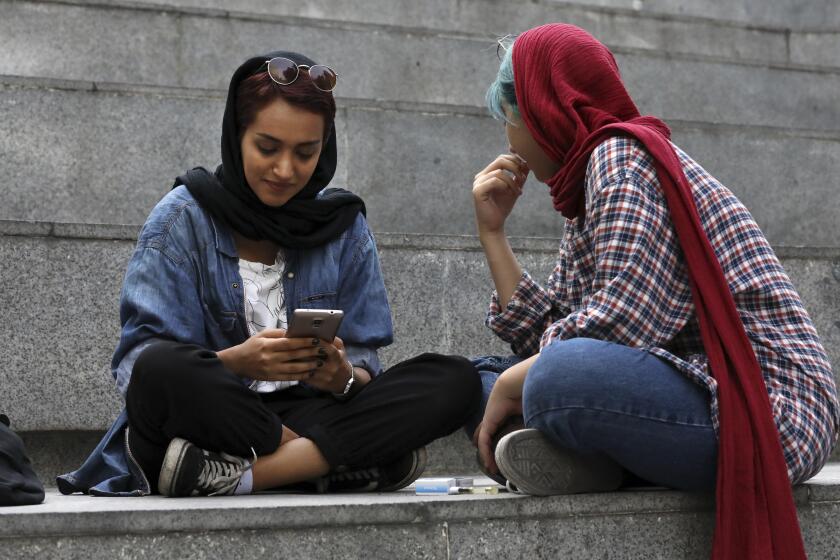In this Tuesday, July 2, 2019 photo, an Iranian woman works on her cell phone while spending an afternoon on steps outside of a shopping mall in northern Tehran, Iran. Before Iranians can check out the latest offerings on Twitter or YouTube, they must scroll through an array of icons on their smartphones, searching for the best workaround to bypass official censors. It’s a cat-and-mouse game that has become second nature in Iran, where the clerically-led government restricts access to popular social media sites and where U.S. sanctions create other barriers.(AP Photo/Vahid Salemi)