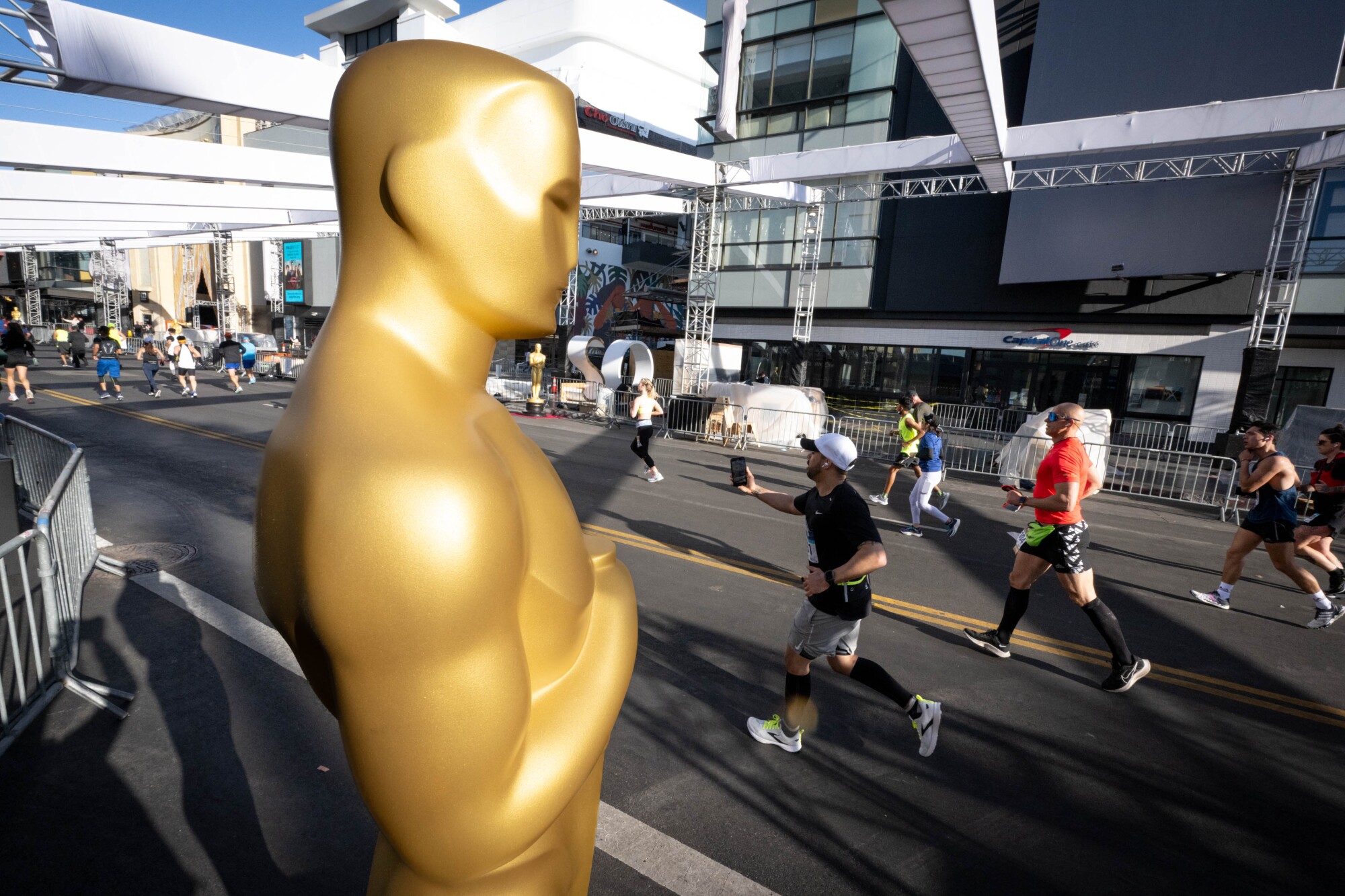 Runners pass a large Oscar statue along Hollywood Boulevard during Los Angeles Marathon.