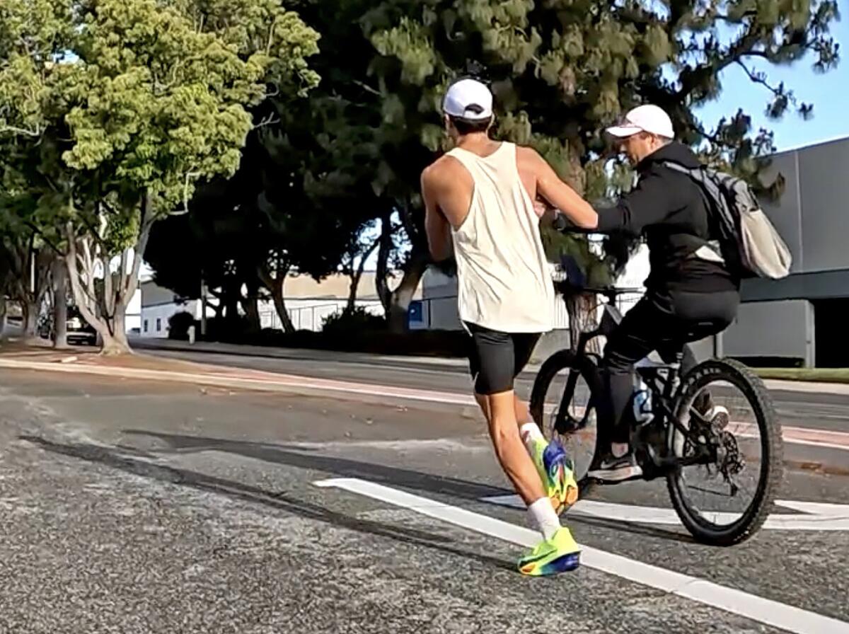 A video screenshot from a cyclist course marshal shows Esteban Prado, left, receiving a bottle of water from his father. 