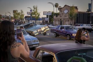 Van Nuys, CA - April 17: People take photos/video and view classic low-rider cars parading down Van Nuys Blvd. during the monthly Van Nuys Cruise Night Van Nuys Blvd. on Saturday, April 17, 2021 in Van Nuys, CA. Cruising is back in a major way in Southern California. The distinctly local custom of leisure drives on urban boulevards in elegant or souped-up vehicles has blossomed during the pandemic, reaching heights of the practice not seen since the heydays of the 1980s and the subsequent crackdown. Car club leaders say they are responsible participants in their community, and lead fundraising drives for kids, relief, and other causes. But neighbors of areas where cruises take place say they feel under siege by the hundreds of vehicles and people who gather, locking down their streets in traffic, and leading to violence or threats. They say their complaints to police and City Hall go unheeded. The scene has also evolved to include so-called "boogies," where a sound system is set up and any parking lot becomes an outdoor dance party. It is parts Chicano vintage culture revival, in the dress and style of the women and men who gather, and part rejection of coronavirus protocols that require social distancing and masks. The scene continues despite the intense toll the pandemic has taken on SoCal Latinos, and some argue such parties and gatherings are super-spreader events. (Allen J. Schaben / Los Angeles Times)