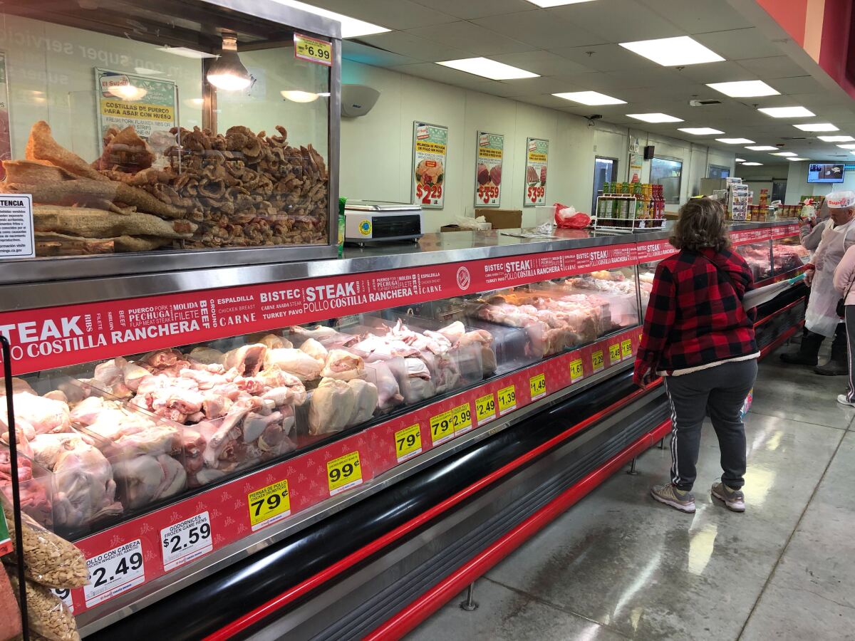 A person waits at the meat counter at a grocery store
